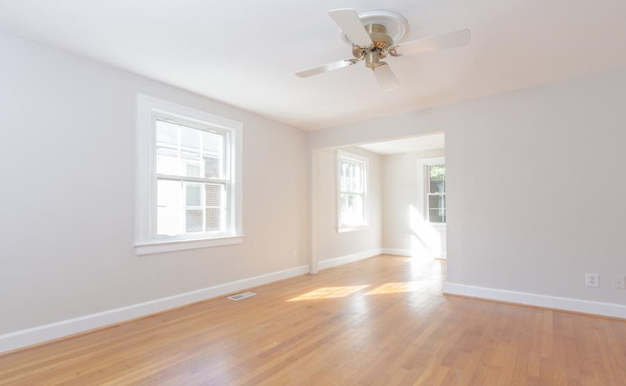 400 Perry Street Raleigh, NC 27608 - Photo 9 of 22 an empty room with wooden floor chandelier fan and windows