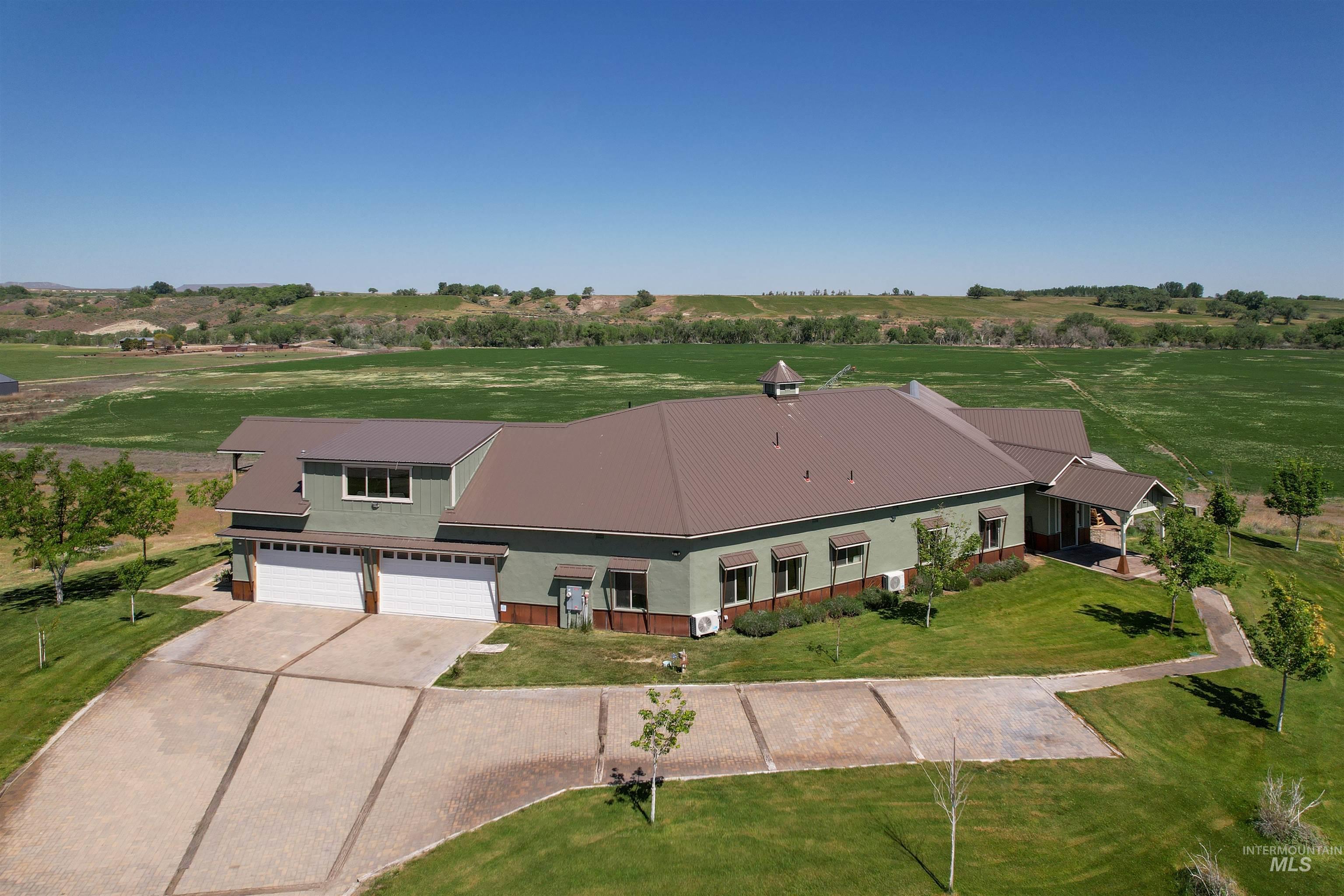 1030 Desert Glen Road Adrian, OR 97901 - Photo 2 of 47 Expansive property featuring a green-sided exterior with a brown metal roof, multi-car garage, and a covered entry