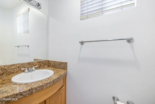 a bathroom with a granite countertop sink and a mirror