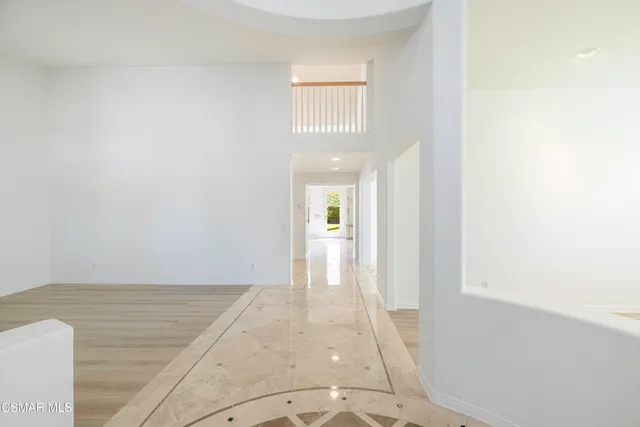 a view of a hallway with wooden floor and a bathroom