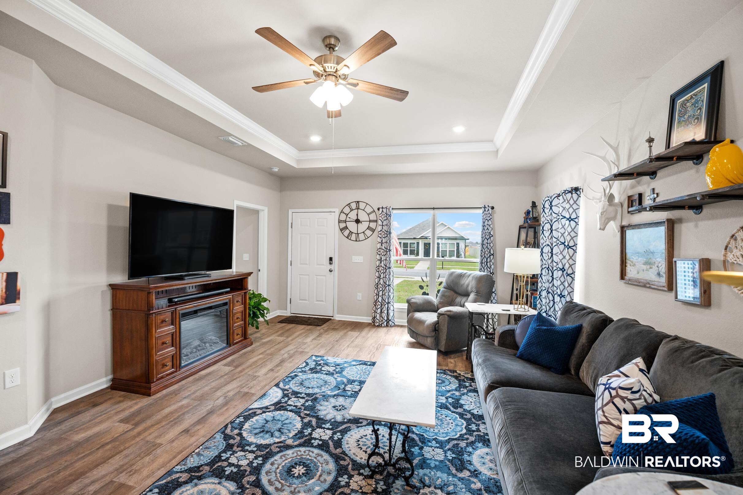 24139 Veranda Circle Elberta, AL 36530 - Photo 6 of 40 Living room with baseboards, ornamental molding, wood finished floors, a glass covered fireplace, and a raised ceiling
