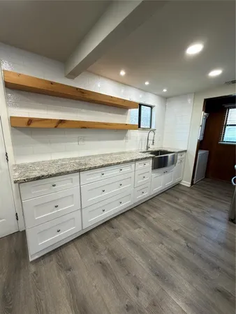 a kitchen with granite countertop white cabinets and stainless steel appliances