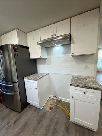 a kitchen with granite countertop white cabinets and stainless steel appliances