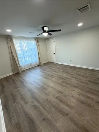an empty room with wooden floor ceiling fan and windows