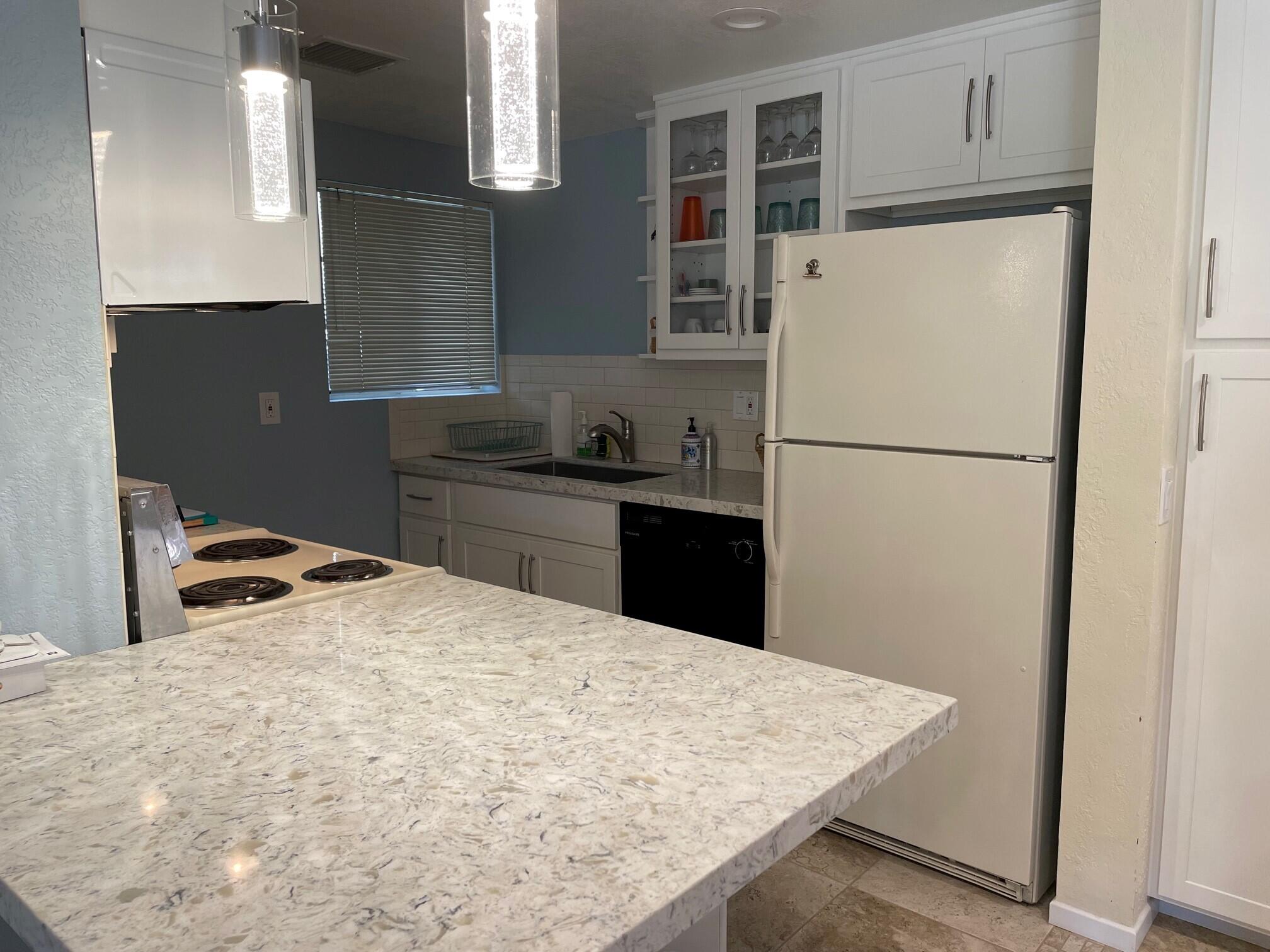 2700 Lawrence Crossley Road, Unit 51 Palm Springs, CA 92264 - Photo 8 of 23 a white kitchen with sink refrigerator and cabinets