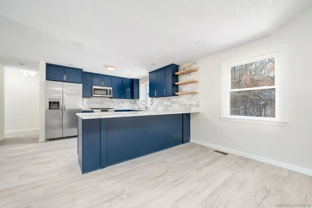 a kitchen with kitchen island granite countertop a sink cabinets and stainless steel appliances