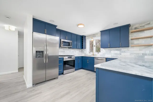 a kitchen with stainless steel appliances granite countertop a refrigerator a sink and a stove