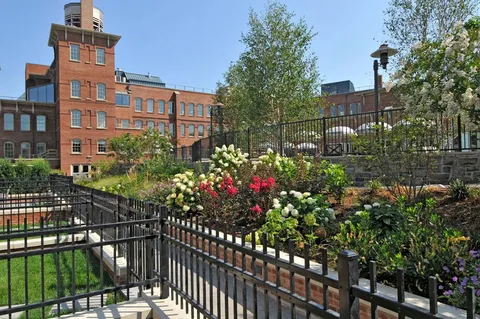 a view of a brick house with a flower garden in front of it