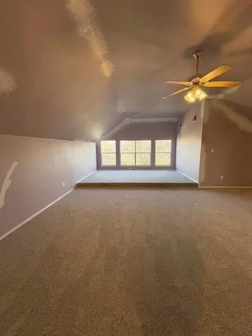 an empty room with windows and chandelier fan