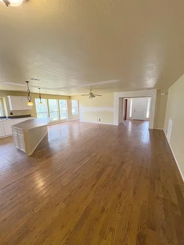 a view of a big room with wooden floor and windows