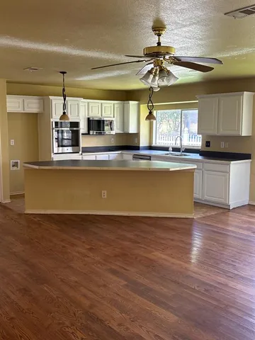 a view of a kitchen with a sink wooden floor and cabinets
