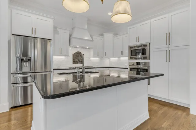 a kitchen with stainless steel appliances granite countertop a sink a stove and a refrigerator