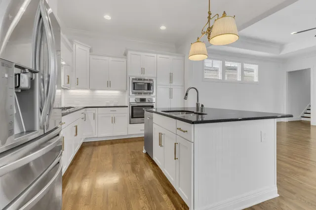 a kitchen with granite countertop a refrigerator a sink and white cabinets