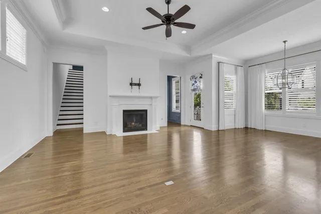 an empty room with windows a fireplace and wooden floor