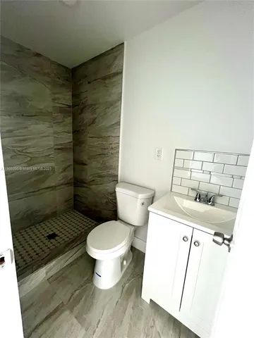 a bathroom with a granite countertop toilet and a sink