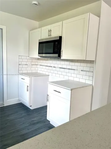 a kitchen with stainless steel appliances white cabinets and a wooden floor