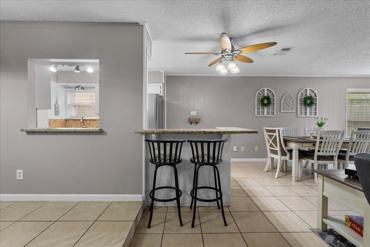 883 Silverpines Road Houston, TX 77062 - Photo 8 of 38 This inviting space features a cozy open-concept design with a breakfast bar and seating area. The dining space is adjacent, offering ample room for gatherings. Neutral tones and tile flooring create a warm, welcoming atmosphere.