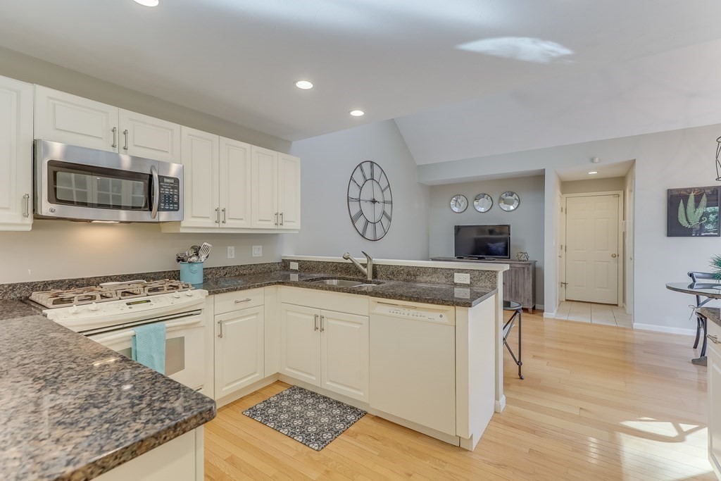 25 Rigsdale Way, Unit 25 Plymouth, MA 02360 - Photo 15 of 38 a kitchen with stainless steel appliances granite countertop a stove top oven a sink a dining table and chairs with wooden floor