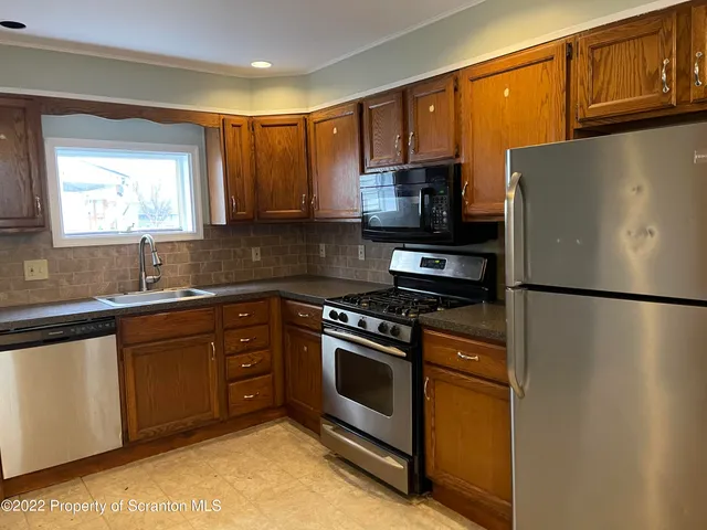 a kitchen with stainless steel appliances granite countertop a refrigerator stove a sink and a microwave