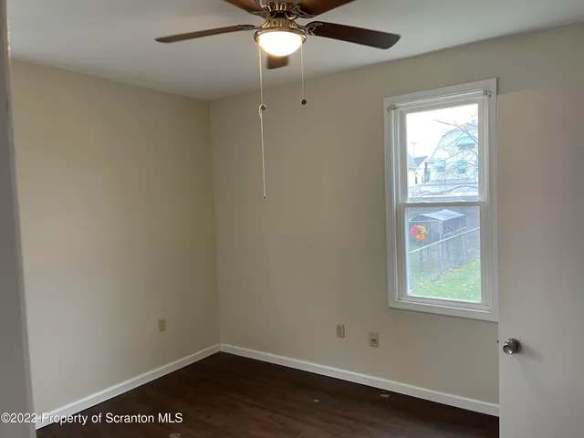 an empty room with a window and wooden floor