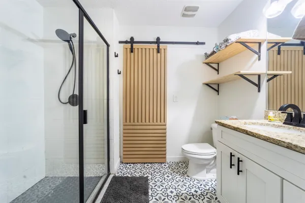 a bathroom with a granite countertop sink a toilet and shower