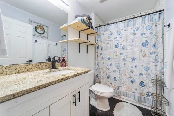 a bathroom with a granite countertop sink a toilet and a shower curtain