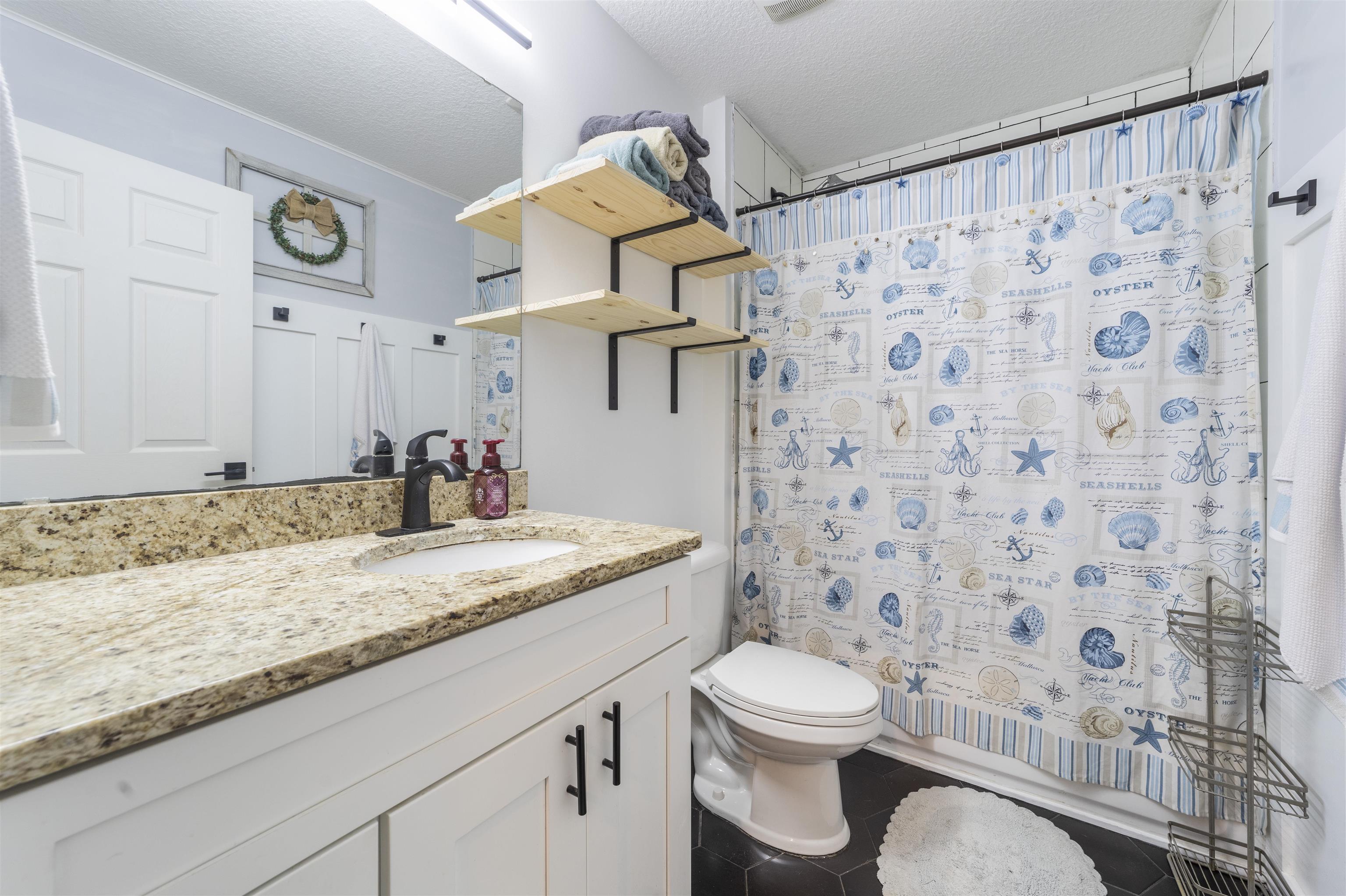101 Azalea Road St. Augustine, FL 32086 - Photo 25 of 35 a bathroom with a granite countertop sink a toilet and a shower curtain