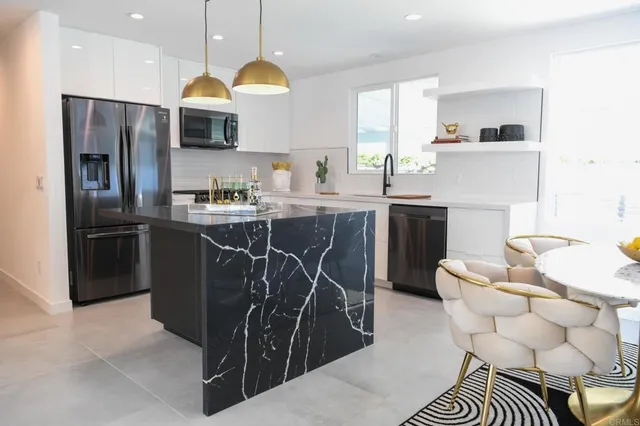 a kitchen with stainless steel appliances a sink a stove a refrigerator cabinets and a dining table