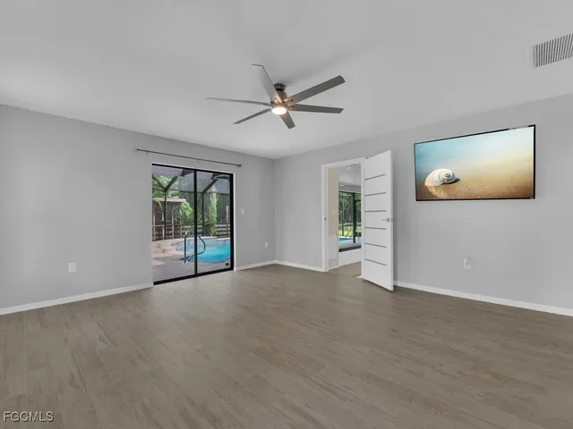 a view of an empty room with a window and a kitchen