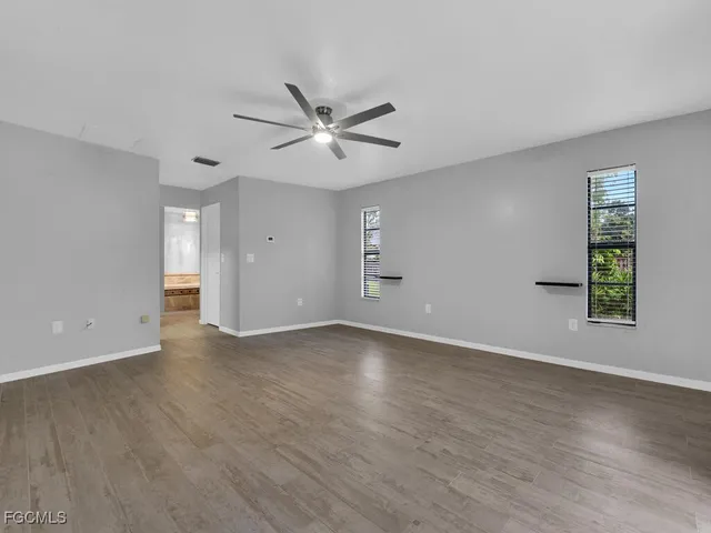 a view of an empty room with a window and wooden floor