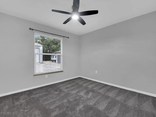 an empty room with a window and a ceiling fan