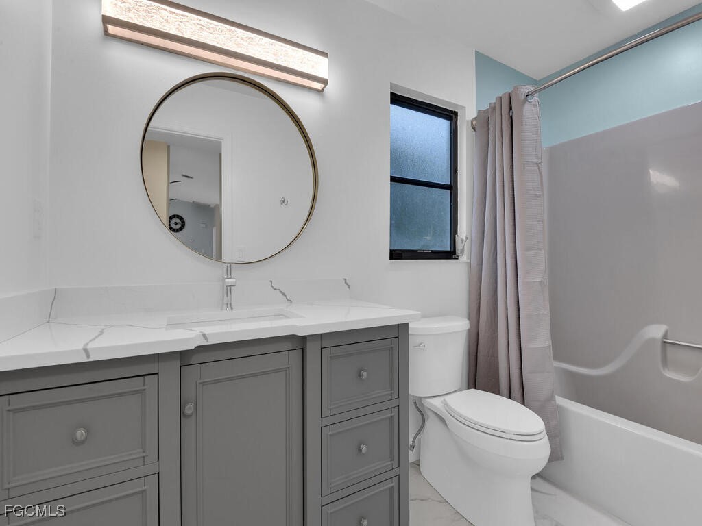 11981 Plantation Road Fort Myers, FL 33966 - Photo 28 of 48 a bathroom with a toilet a sink and mirror