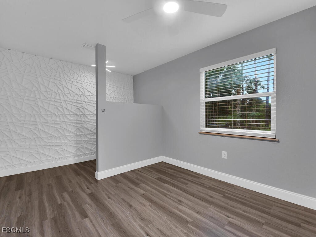 11981 Plantation Road Fort Myers, FL 33966 - Photo 29 of 48 a view of an empty room with wooden floor and a window