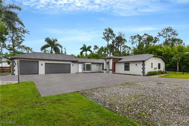 a view of a house with a yard and a large tree
