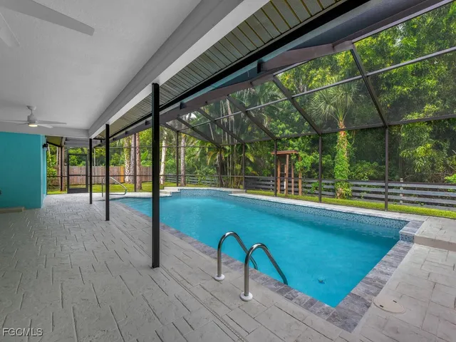 a view of swimming pool with seating space and wooden fence