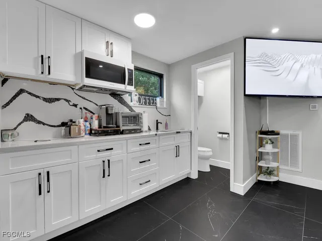 a kitchen with white cabinets and sink