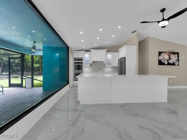 a large kitchen with stainless steel appliances granite countertop a large window and a glass door