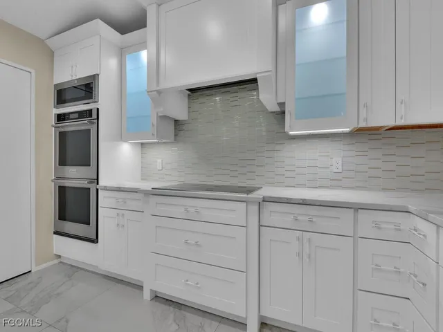 a kitchen with white cabinets and stainless steel appliances