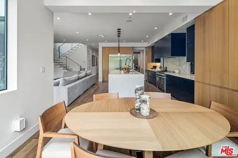 a kitchen with stainless steel appliances kitchen island granite countertop a sink a refrigerator and chairs