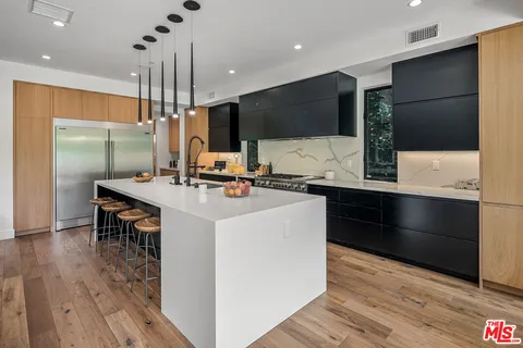 a kitchen with stainless steel appliances kitchen island granite countertop a sink a stove and a refrigerator