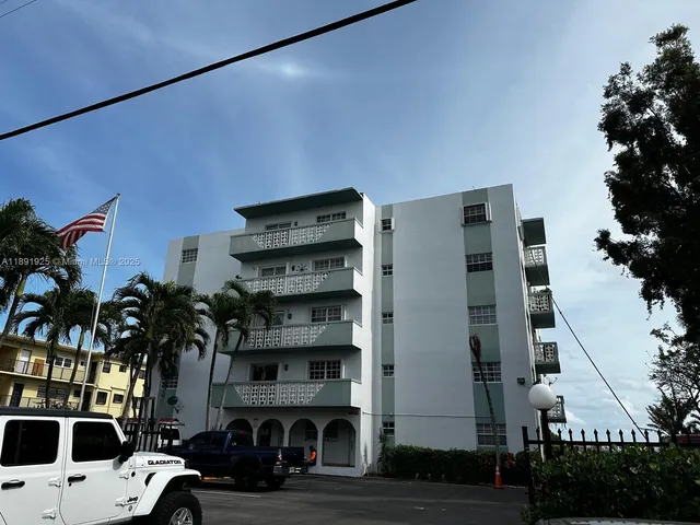 a front view of a building with streets and trees