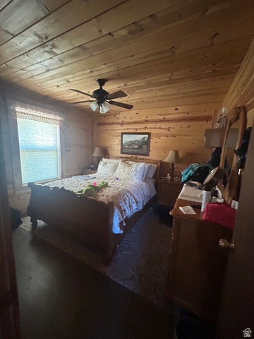 19075 West Honesty Cove Duchesne, UT 84021 - Photo 13 of 44 Bedroom featuring natural wood-paneled walls and ceiling, dark wood-finish flooring, and a ceiling fan with integrated lighting
