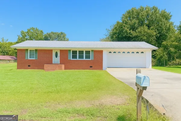 a front view of house with yard and trees in the background