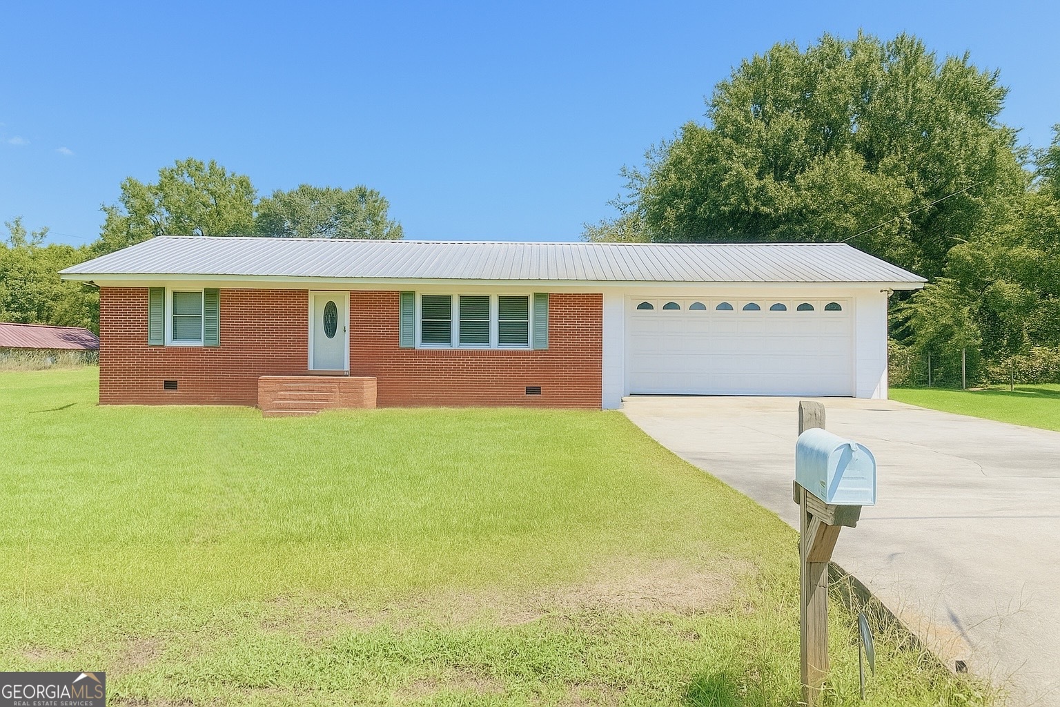 a front view of house with yard and trees in the background