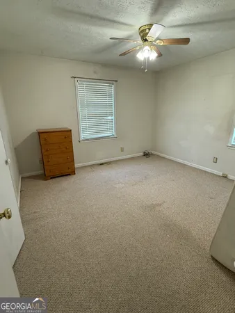 an empty room with windows and fan