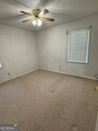 an empty room with a chandelier fan and windows