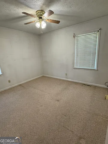 an empty room with a chandelier fan and windows