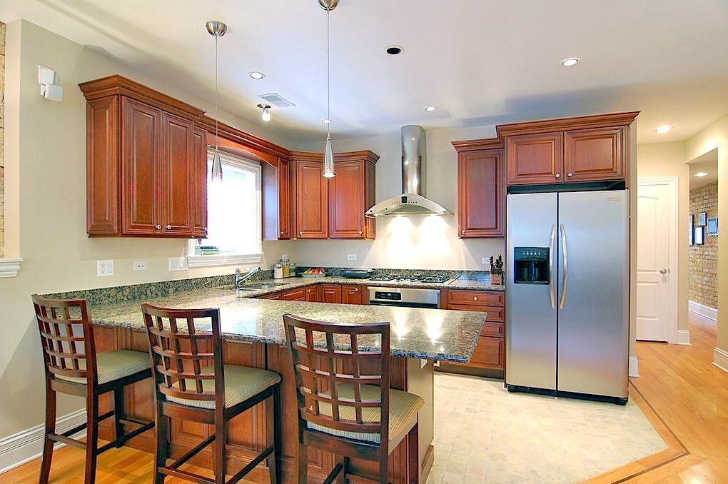Undisclosed Address Chicago, IL 60613 - Photo 3 of 8 a kitchen with stainless steel appliances granite countertop a refrigerator a stove a sink a dining table and chairs with wooden floor