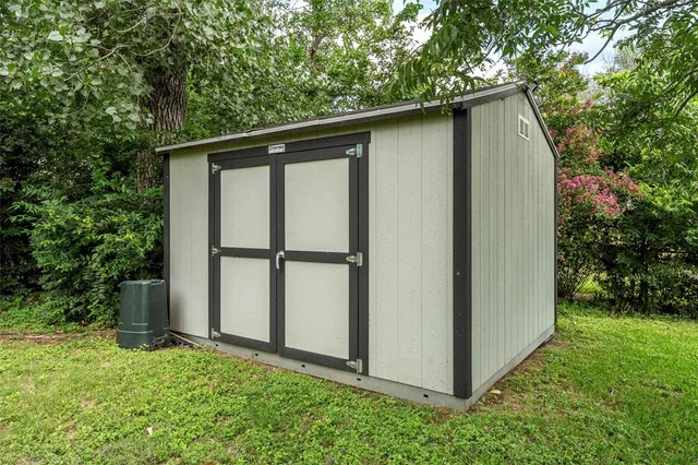 a backyard of a house with plants and large tree