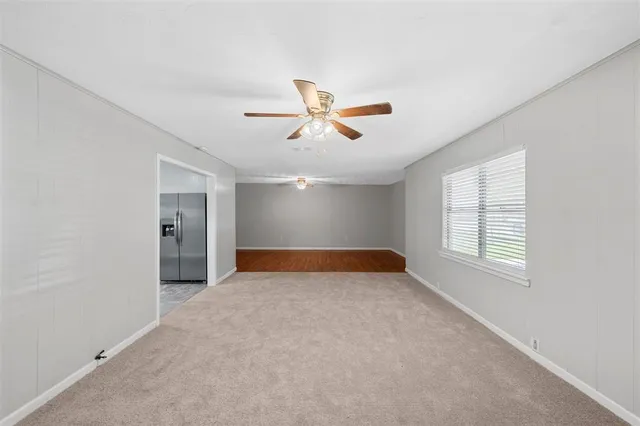 an empty room with chandelier fan and windows